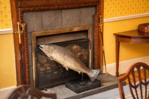 Deep-fried fish sculpture at Erchless Castle Estate, traditional decor with fireplace and wooden furniture.