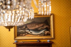 Elegant Erchless Castle Estate interior with vintage fishing artwork and luxurious chandelier.