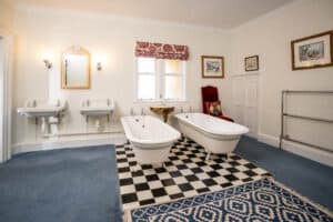 Elegant vintage bathroom with twin sinks and clawfoot baths at Erchless Castle Estate.