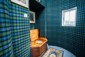 Traditional Scottish-style toilet room at Erchless Castle Estate with tartan wallpaper.