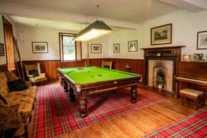 Luxurious snooker room at Erchless Castle Estate with traditional decor and vintage fireplace.