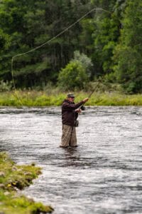 Fly fishing at Erchless Castle Estate in the Scottish Highlands, surrounded by lush greenery and scenic river views.