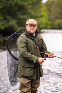 Man fishing at Erchless Castle Estate, scenic outdoor activity in Highland UK.