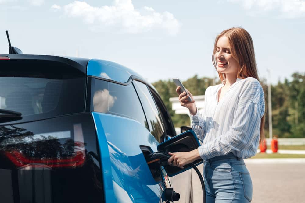EV charging station with a woman charging her electric vehicle outdoors.