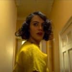 Marianne (Jessica Brown Findlay), the lead character of The Banishing, turns around to look behind her. She looks scared and concerned.