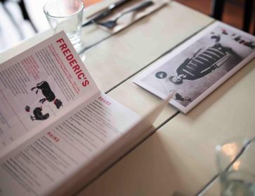 Close-up of Frederic's restaurant menu on a table, showcasing food and drink options.
