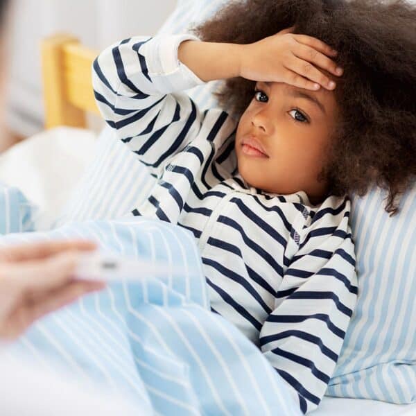 Child with flu-like symptoms lying in bed, seeking immune support.