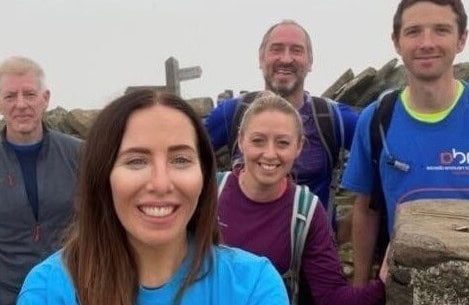 Happy group of hikers taking a selfie outdoors during a day hike, dressed in casual sportswear and backpacks, enjoying nature and good company.