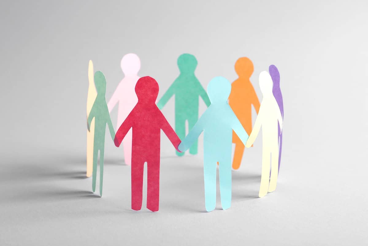 Colourful paper cut-out human figures holding hands in a circle.
