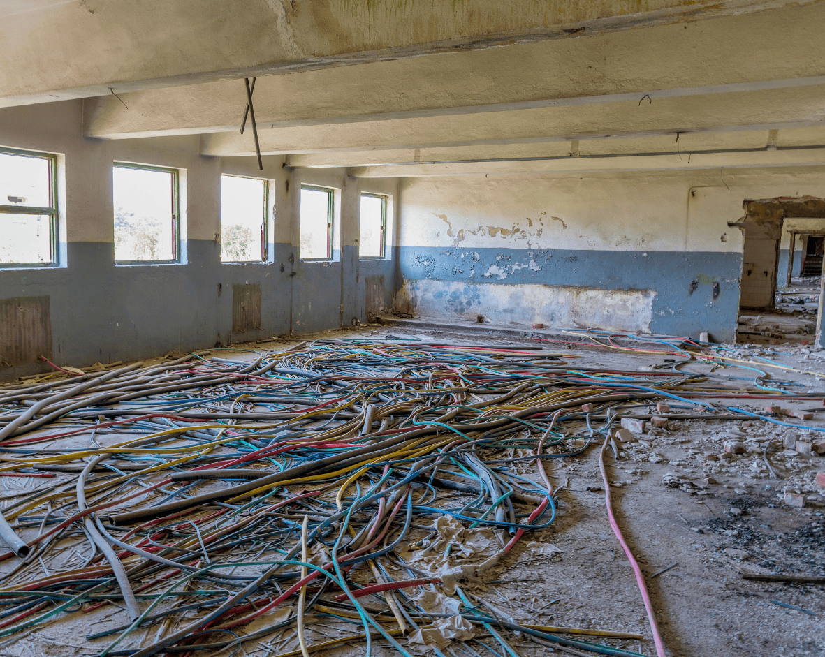 1. Disorganized electrical wiring and cables on a dusty construction site in a building under renovation.