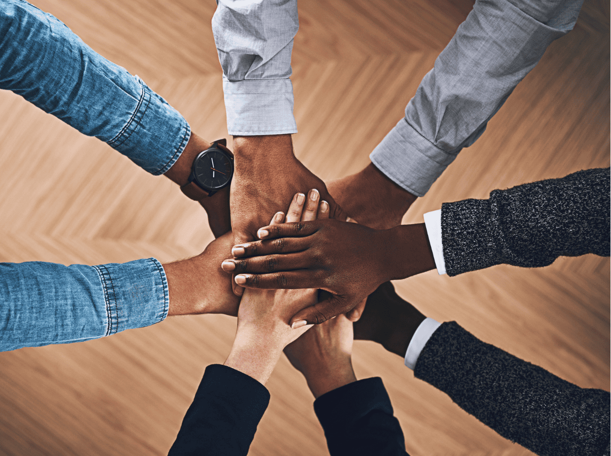 Diverse hands stacked together symbolising unity and collective effort.