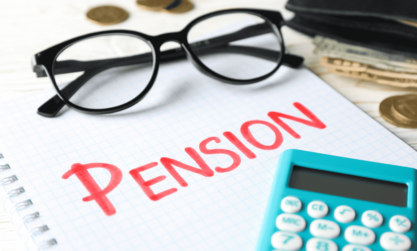 A pair of black glasses, a calculator, and a notebook with 'PENSION' written in red, symbolising financial planning for retirement.