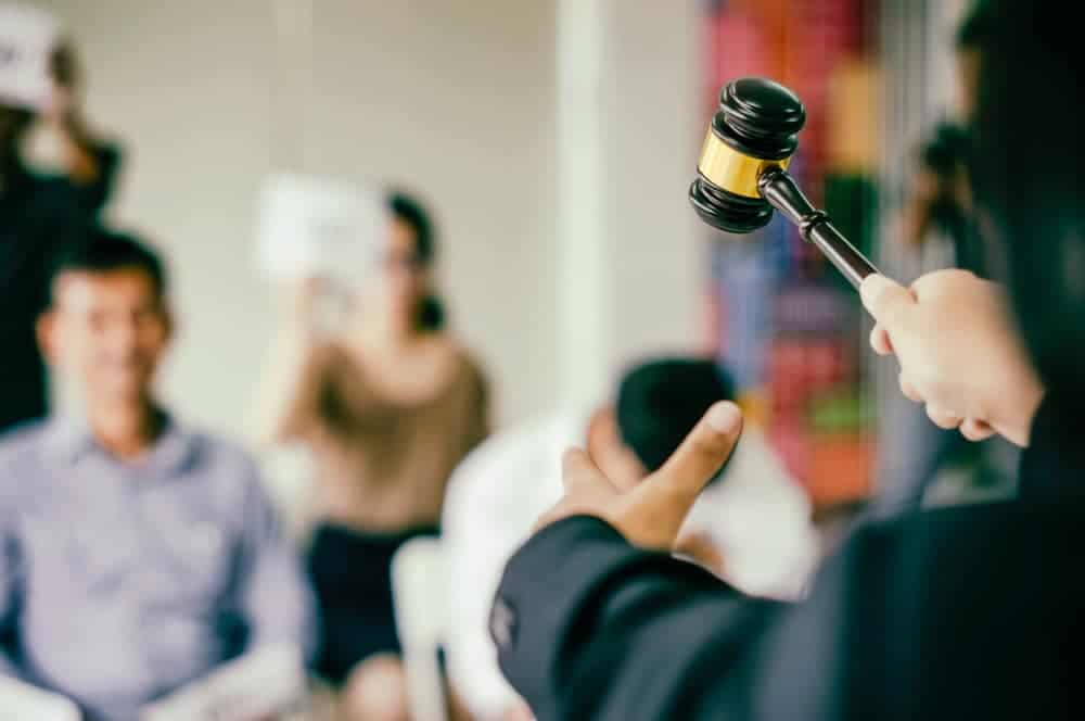 Auctioneer holding gavel during property auction presentation.