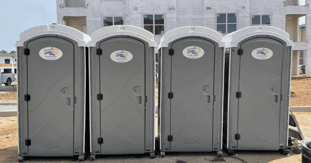 Row of portable restrooms at a construction site for workers' convenience.