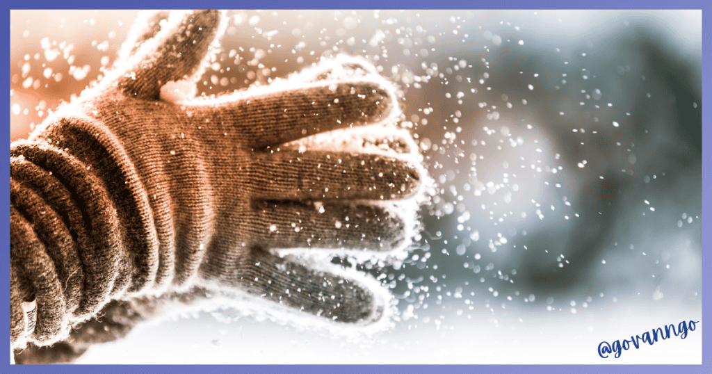 Person wearing gloves handling snow or ice for winter tank prep.