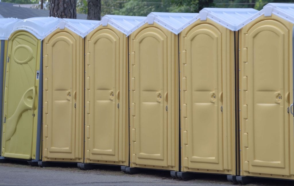 Row of yellow portable toilets for event sanitation needs.