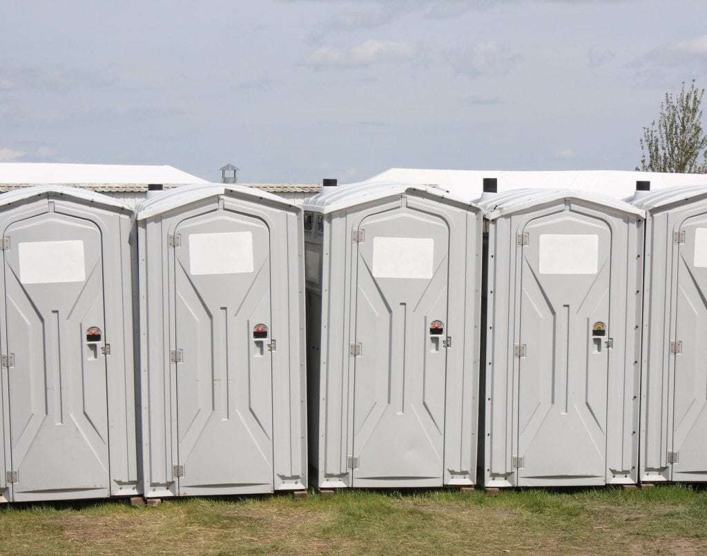 Row of portable toilet units outdoors for sanitation needs.