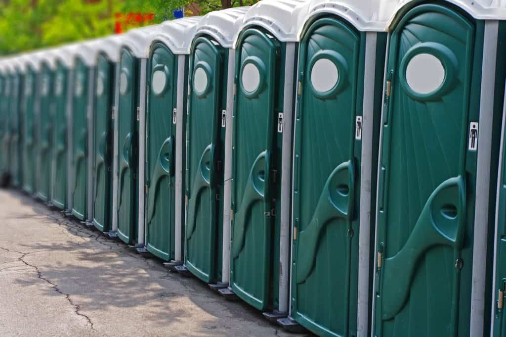 Row of green portable toilets for events or construction sites.