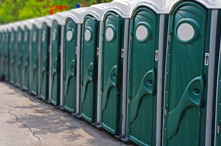 Row of green portable toilets for events or construction sites.