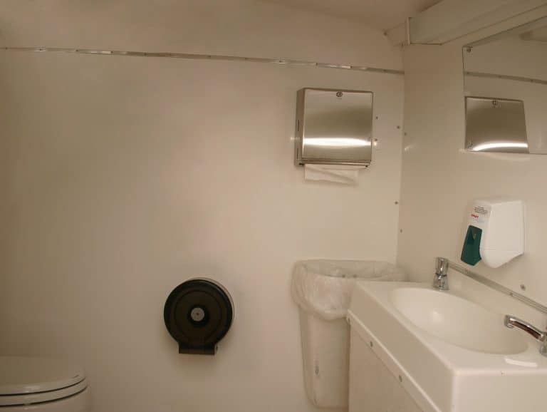 Modern portable restroom with sink, mirror, and hand dryer for events.