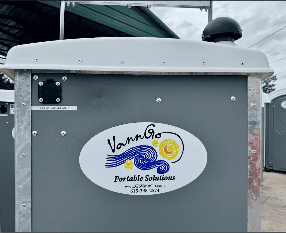 Close-up of a VannGo portable toilet with the company logo and phone number