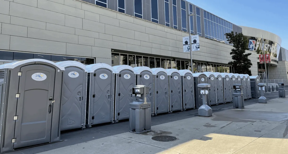 Standard VannGo porta potties lined up outside a commercial building