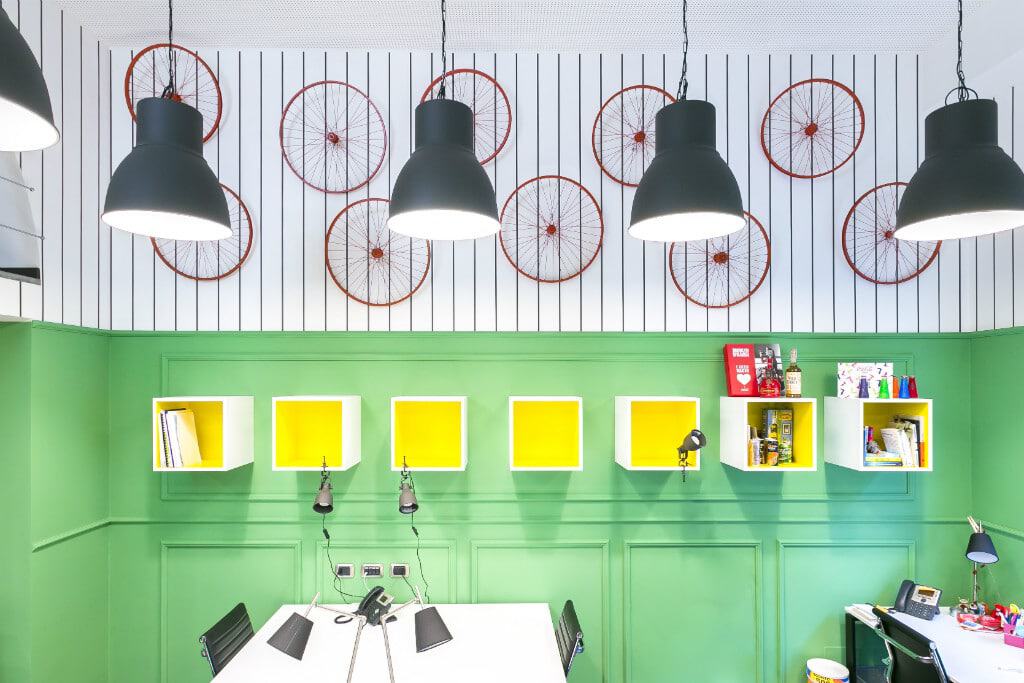 Colorful coworking space with green walls, modern lighting, and decorative wall art.