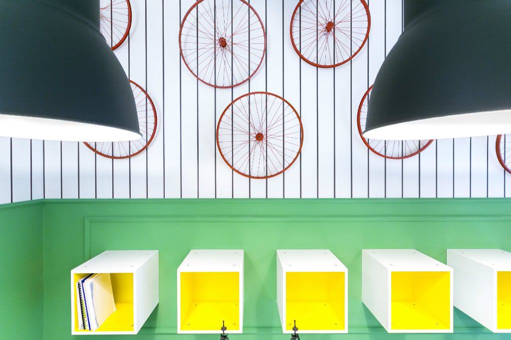 Colorful coworking space with green wall, yellow shelves, and bicycle wheel decor.