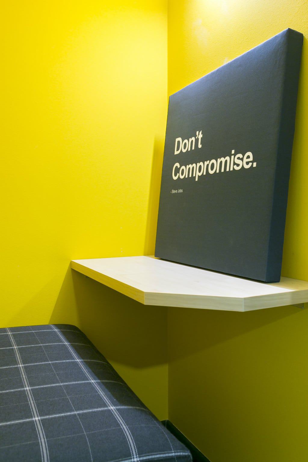 Motivational quote 'Don't Compromise' on a black canvas in a modern coworking space.