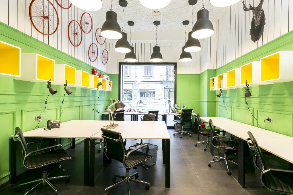 Colorful coworking space with green walls, yellow shelves, and modern lighting.