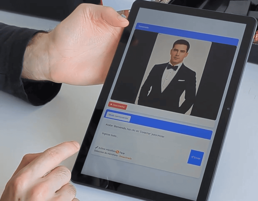 Tablet showing a video chat with a man in a black tuxedo; on-screen status 'Conectado', red 'Desconectar' button and blue bars with Spanish prompts.