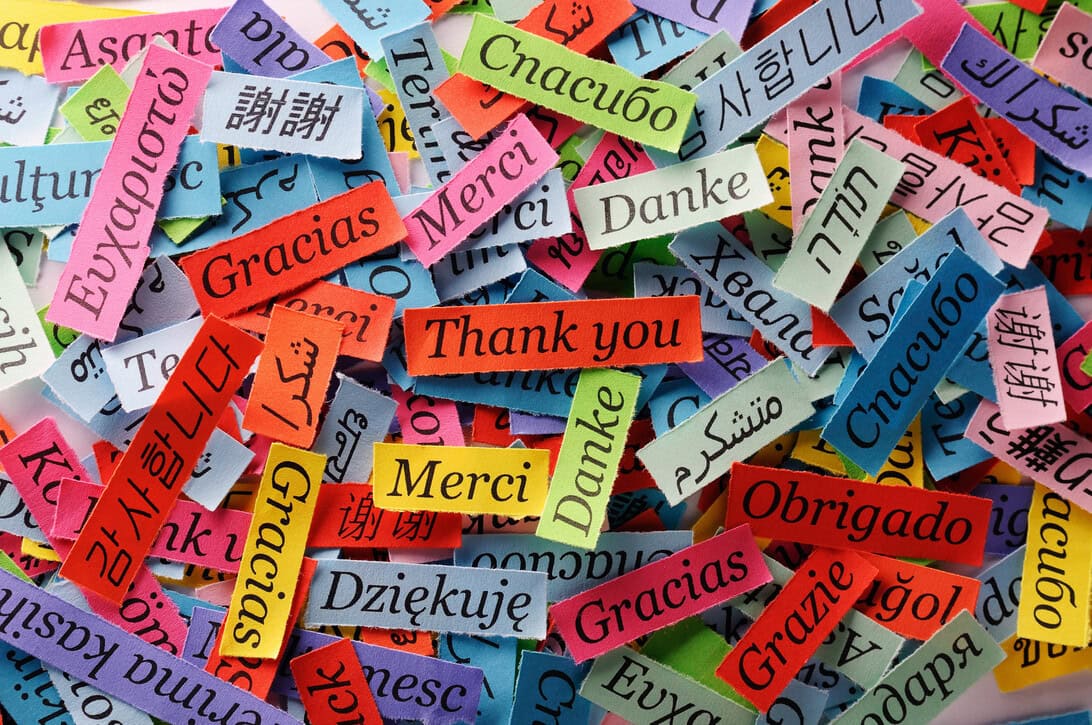 Colorful slips of paper with 'Thank you' messages in multiple languages scattered in a pile.