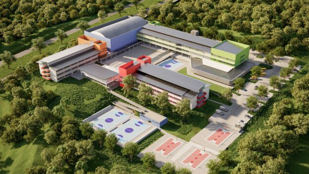 Aerial view of a modern multi-building campus with colorful facades (orange, blue, red, green), surrounded by trees and outdoor courts/fields.