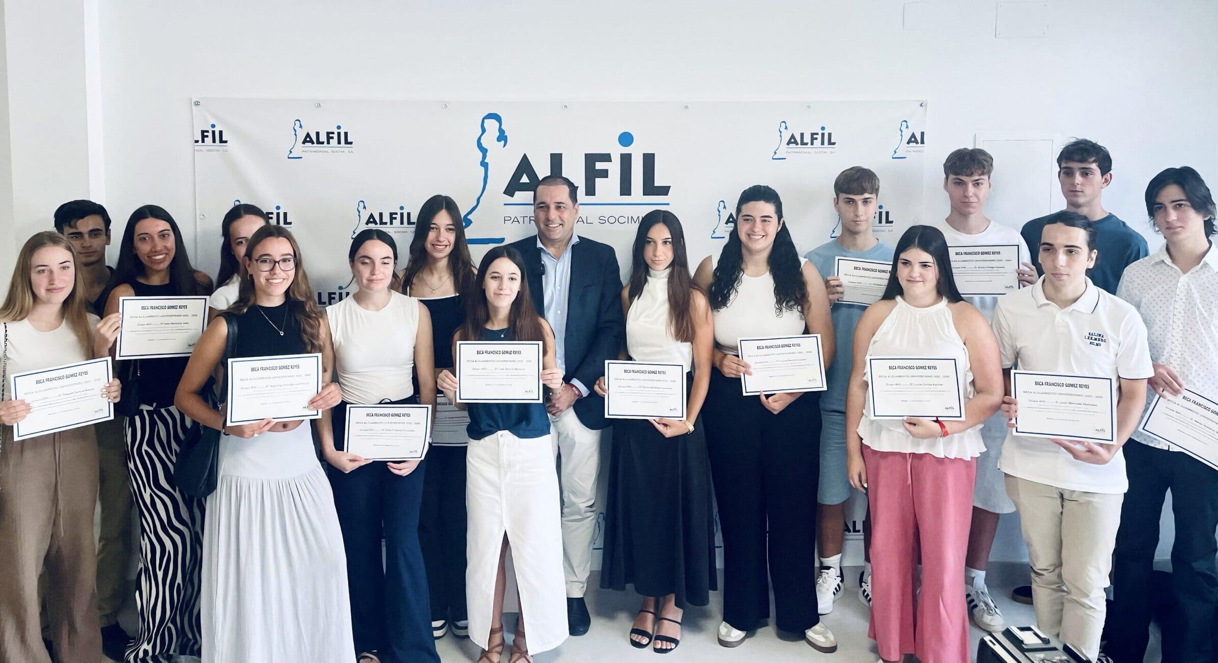 Group of students and a man posing with certificates at a ceremony in front of an ALFIL banner.