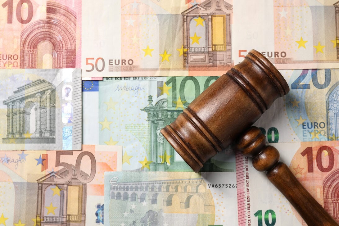 Wooden gavel resting on a spread of euro banknotes, symbolizing legal or financial rulings