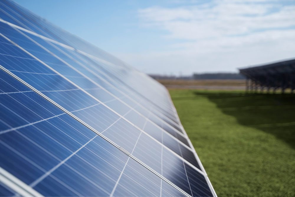 Solar panels installed on a grassy field under a blue sky, capturing sunlight. (Informative)