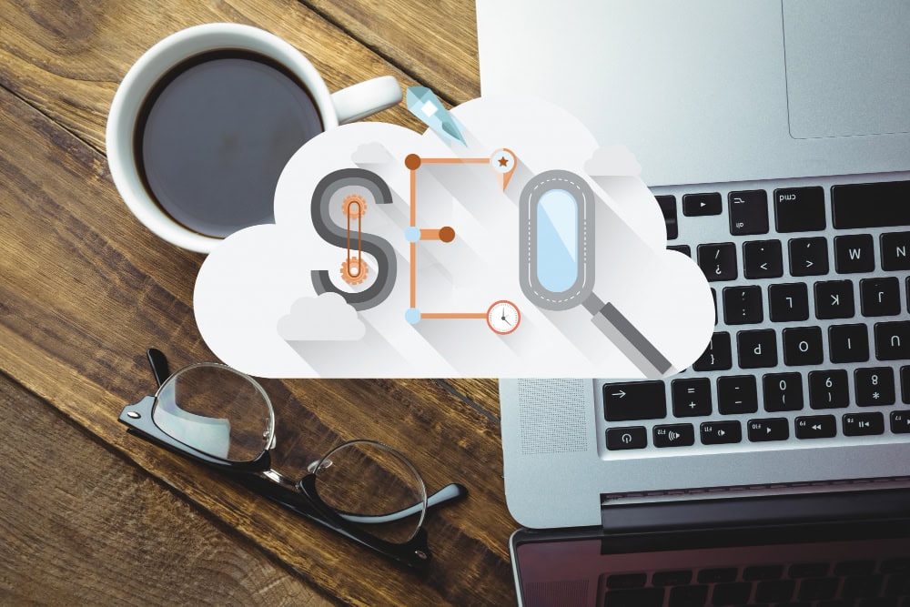 Cloud-themed infographic for SEO over a desk with a coffee mug, glasses, and a laptop keyboard, symbolizing cloud-based optimization work