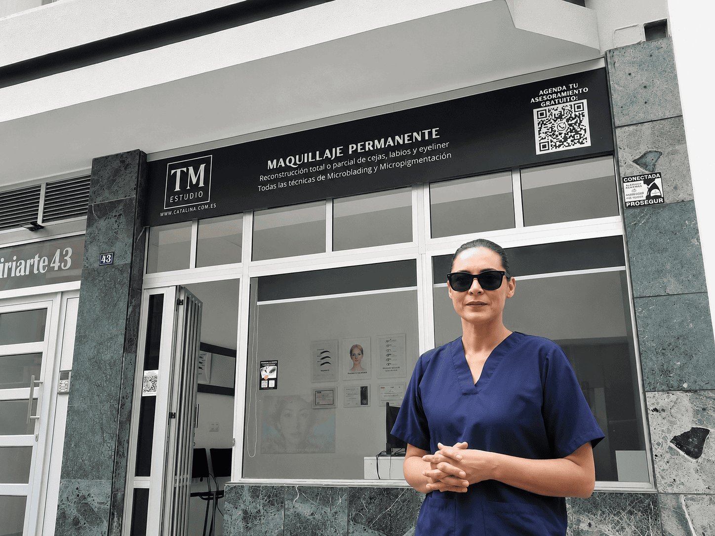 Professional in blue scrubs with sunglasses stands outside a medical aesthetics clinic offering permanent makeup services.
