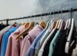 Rows of pastel-colored jackets on hangers along a metal clothing rack in a shop.