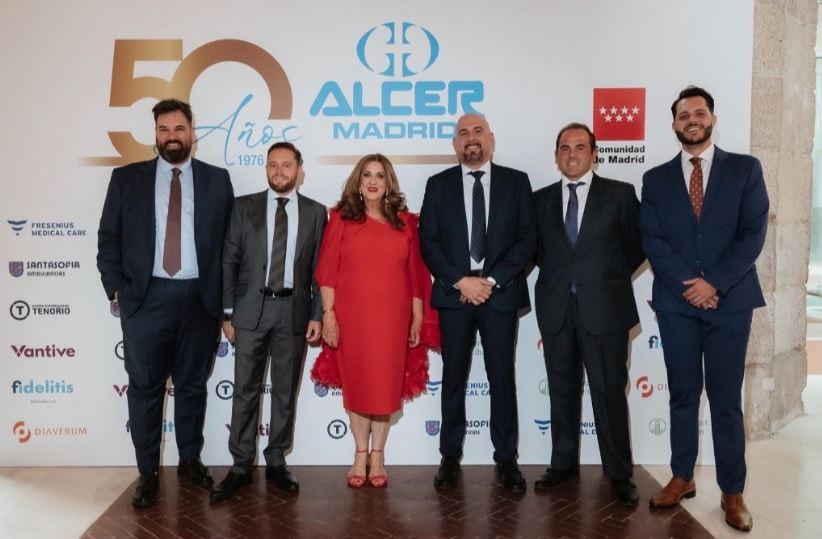 Six people in formal attire pose for a photo at an event celebrating 50 years of ALCER Madrid, with a branded backdrop behind them.