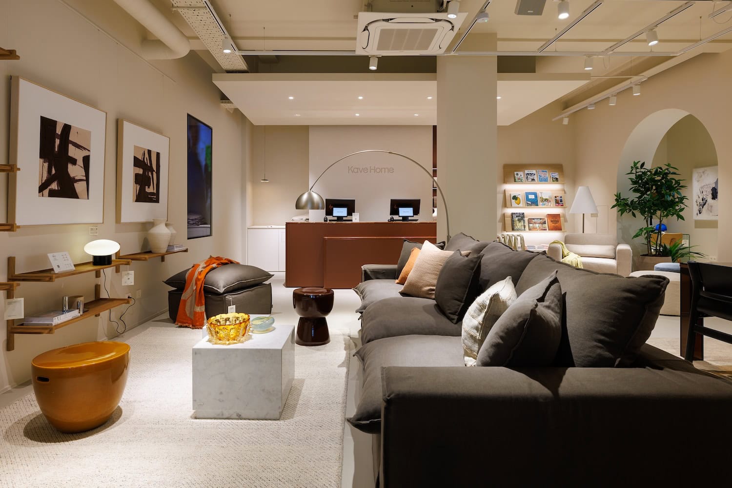 Cozy modern showroom living area with a gray sectional sofa, throw pillows, and a marble coffee table in the foreground.