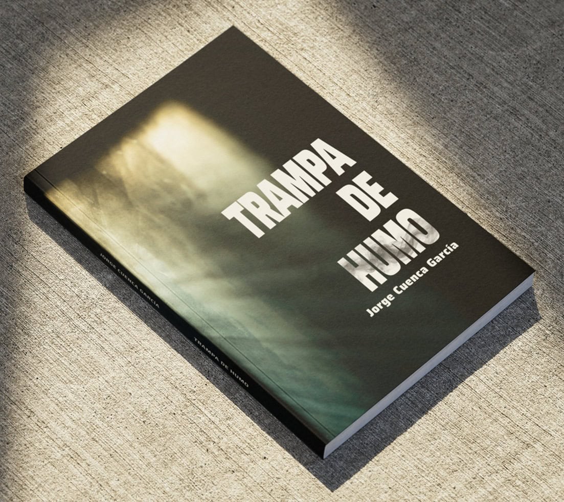 Hardcover book titled 'Trampa de humo' by Jorge Cuenca Garcia resting on a textured gray surface.