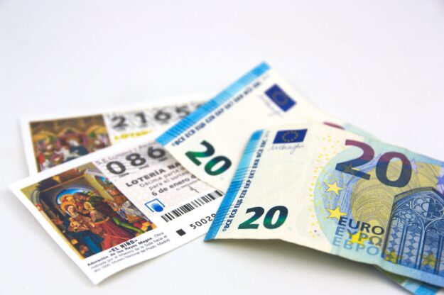 Several euro banknotes fanned out on a white surface, showing denominations like 20 and 50.