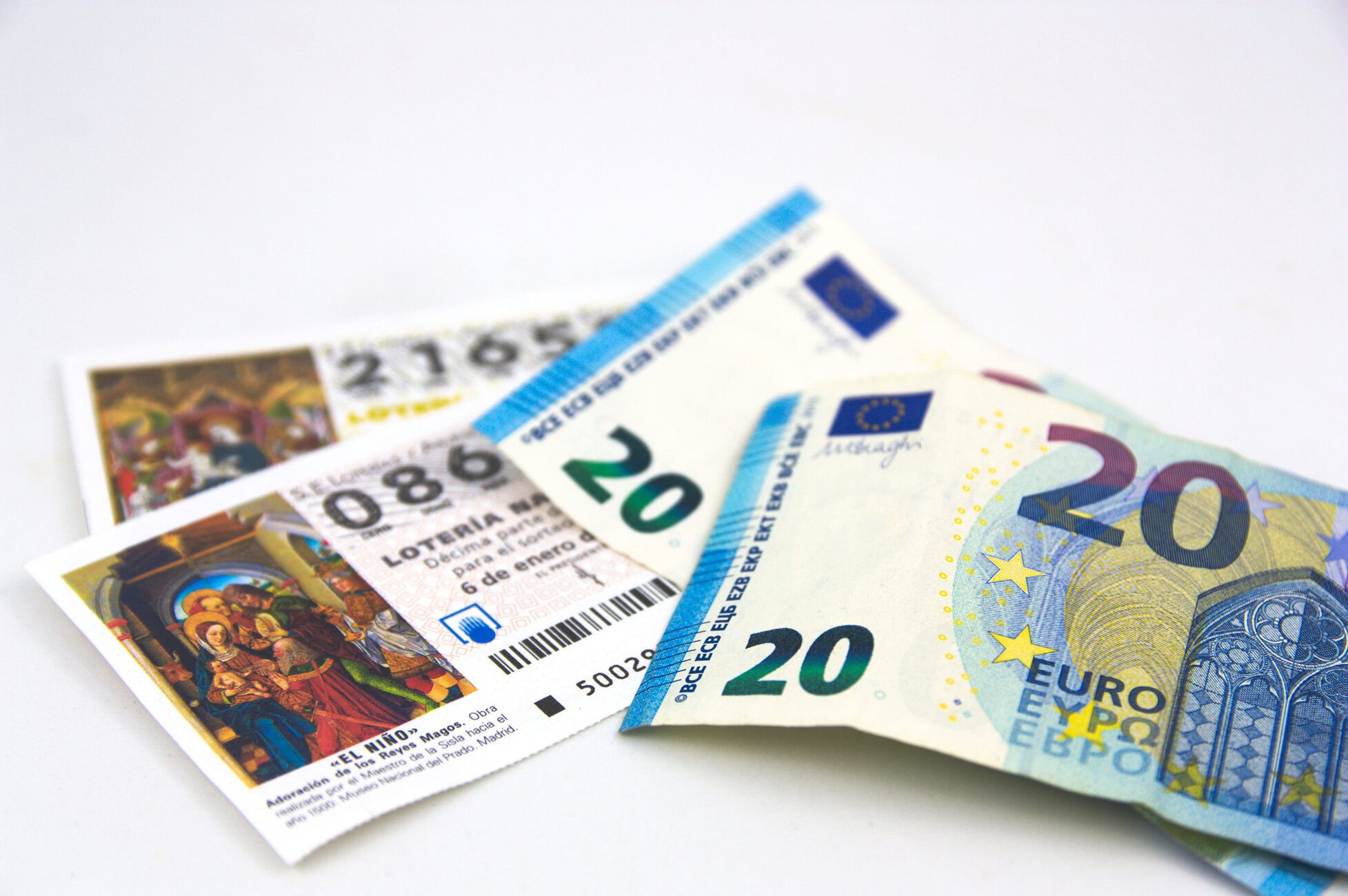 Several euro banknotes fanned out on a white surface, showing denominations like 20 and 50.