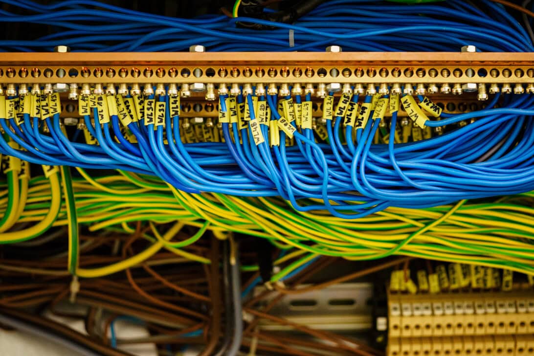 Blue and yellow Ethernet cables plugged into a patch panel in a server rack, with labeled cable tags visible.