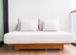 White cushioned outdoor sofa with two pillows on a wooden base, placed on a balcony next to a glass railing.”, “Minimalist white lounge sofa with beige cushions on a wooden platform against a light wall and sliding door.”, “Outdoor daybed with white cushions and a wooden frame on a balcony.”, “Two pillows rest on a white sofa on a wooden platform on a balcony with glass railing.”]}} )?Oops. Need proper JSON without quotes issues. Ensure valid JSON. Let's redo.```json ...``` Remove stray characters.```json{