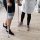 Person with a knee brace using crutches during physical therapy, with a clinician nearby for support.