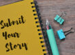 Yellow spiral notebook reading 'Submit Your Story' beside a teal pen and binder clips on a wooden desk.