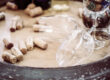 Corks scattered on a wooden barrel with a tilted wine glass nearby, suggesting a wine tasting scene.