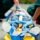 Paramedics secure an injured person on a yellow stretcher with blue straps on a street side.